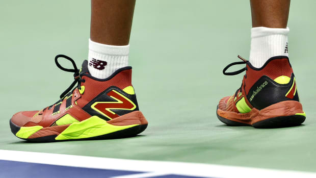 Side view of Coco Gauff's red, brown, and yellow New Balance tennis shoes.